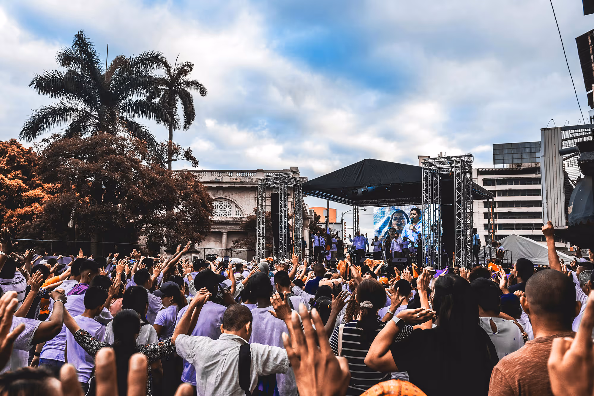 Lively crowd raising their hands toward a stage